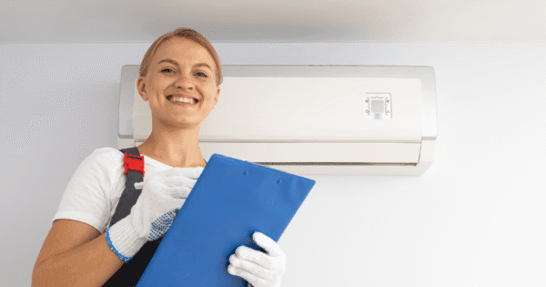 A woman expert is smiling happily while checking a list after cleaning different types of air conditioners.