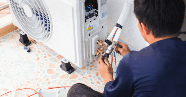 Common air conditioning problems - professional AC technician repairing on the outdoor AC unit to fix performance issues.