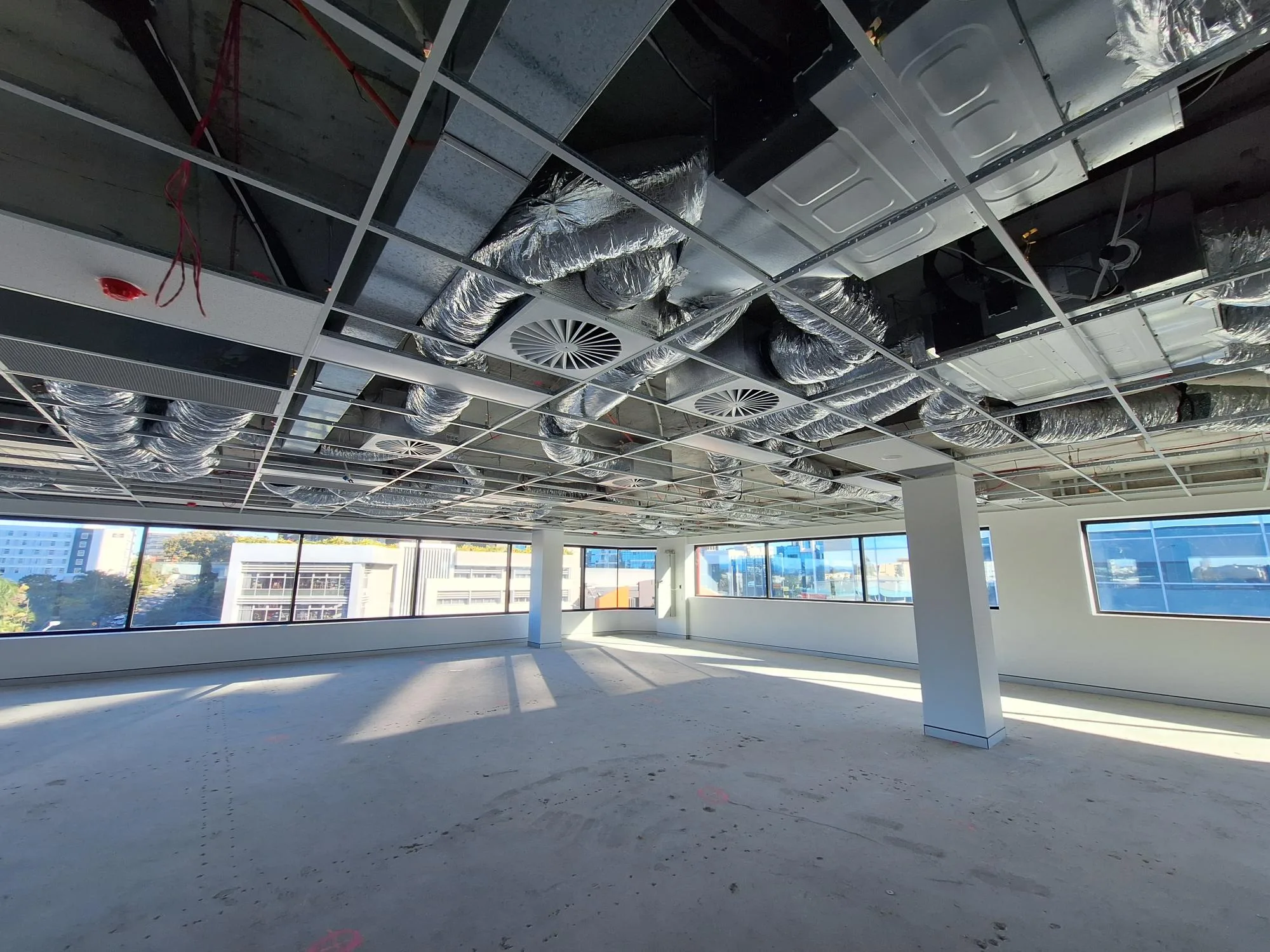 Technician inspecting air conditioning ducts during installation in a commercial building, illustrating air conditioning installation services in Gold Coast.