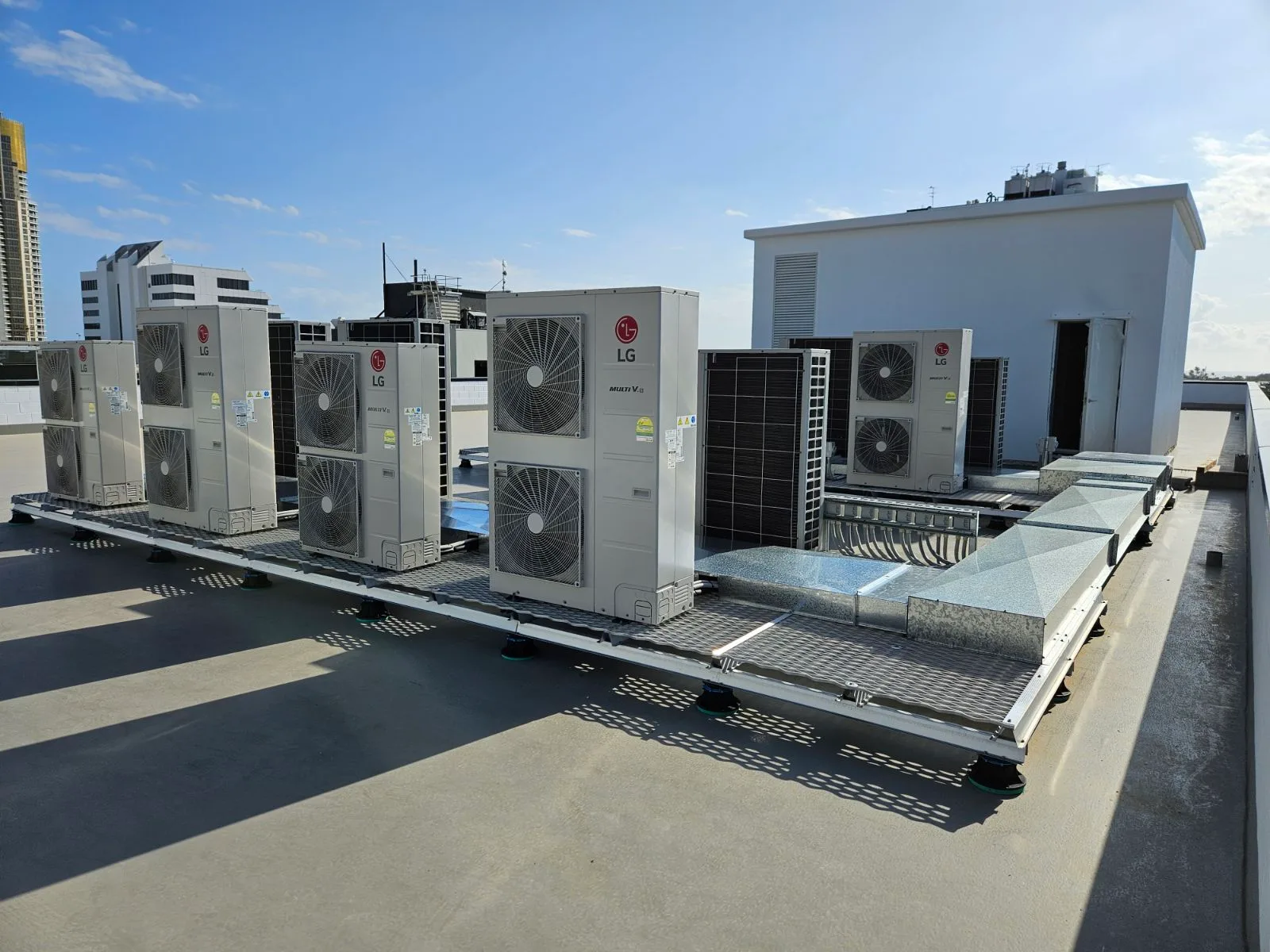Rooftop air conditioning system installations on a modern commercial building, showcasing multiple LG units and ventilation ducts, representing air conditioning repair services in Gold Coast.