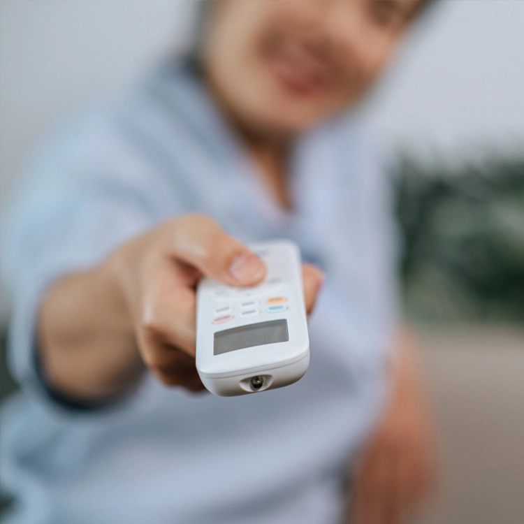 About DEEPCHILL: Customer holding an air conditioning remote control, representing user-friendly HVAC services provided by DEEPCHILL.