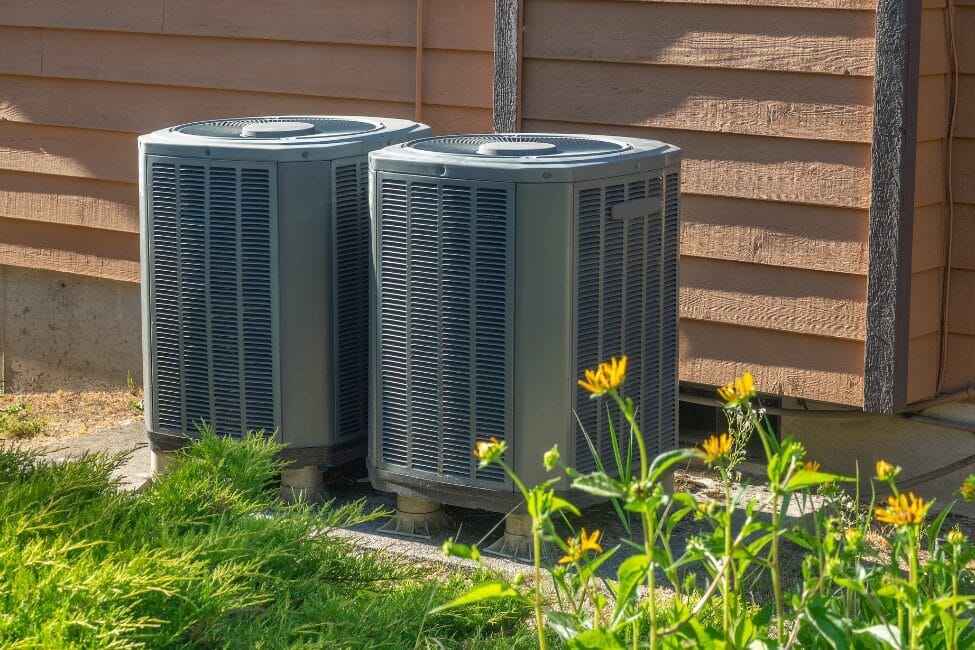 Outdoor HVAC systems surrounded by vegetation, potentially affected by environmental factors when HVAC stops working suddenly.