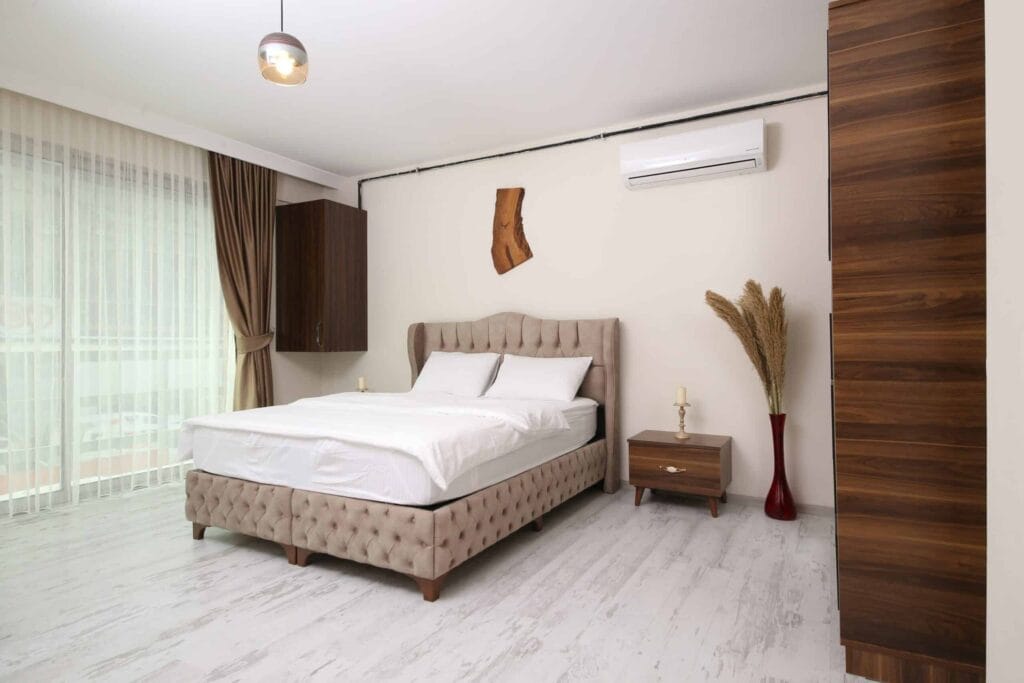 Bright, modern hotel room with a split AC unit on the wall, highlighting the benefits of AC in hotel rooms such as clean air and ideal temperature control.