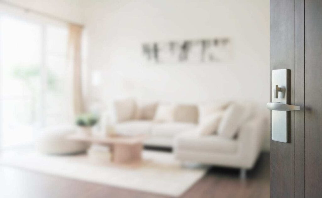 Blurred view of a cozy living room seen through a partially open door, illustrating the choice to leave doors open or closed for comfort or privacy.