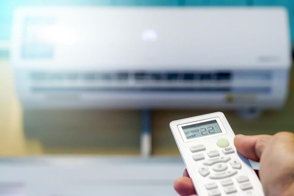 Adjusting temperature on split system air conditioner using remote control set to 22°C.