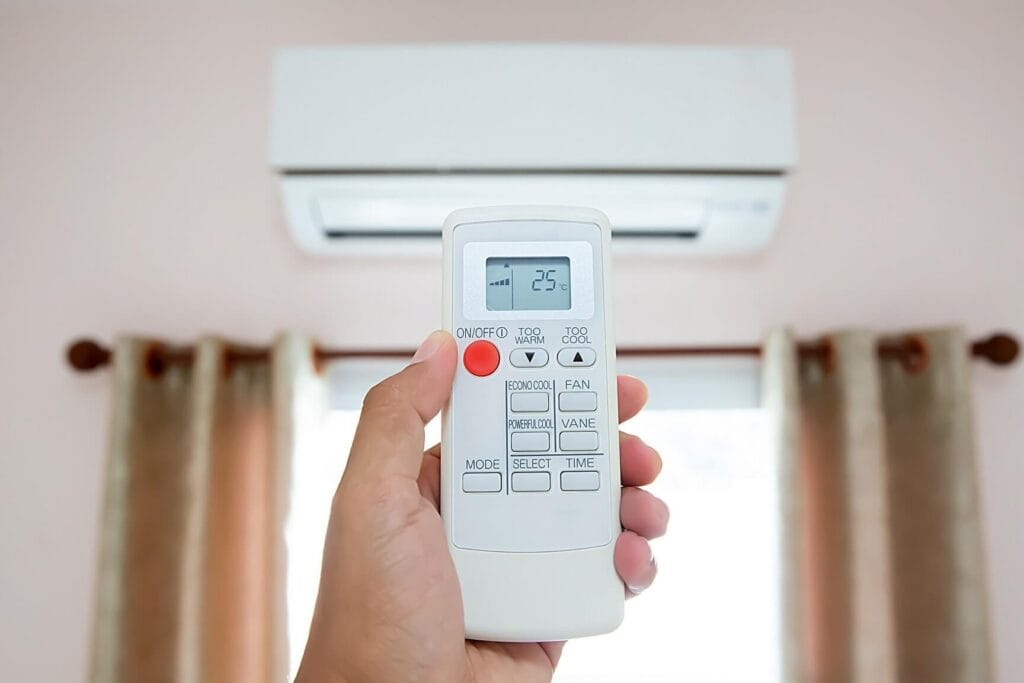 Hand pointing an AC remote at a unit, showing Econo Cool and Powerful Cool buttons—hidden features in your AC remote.