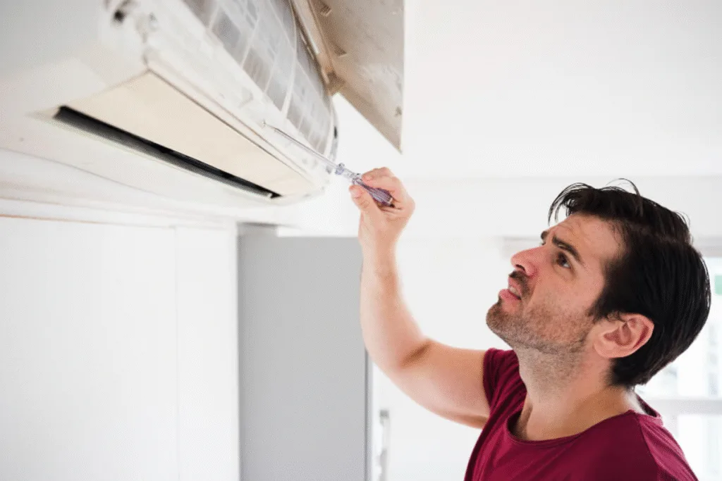 Technician inspecting an AC unit to troubleshoot why the aircon light is blinking at startup — a common air conditioning repair issue.