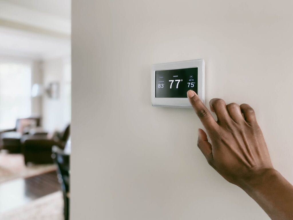 A person adjusting a smart thermostat, possibly making common heating mistakes by setting temperatures inefficiently.