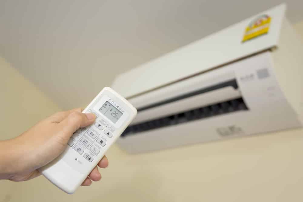 Setting the air conditioner temperature for bedroom using a remote during winter.