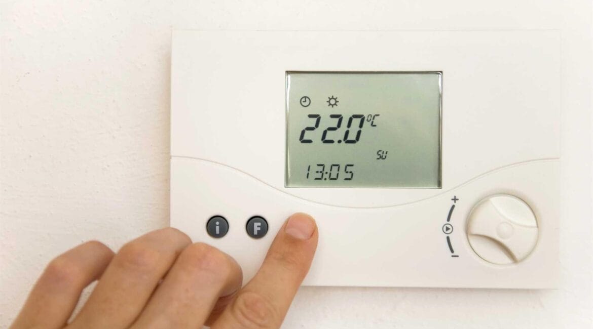 Adjusting the air conditioner temperature for bedroom to 22°C on a wall thermostat.