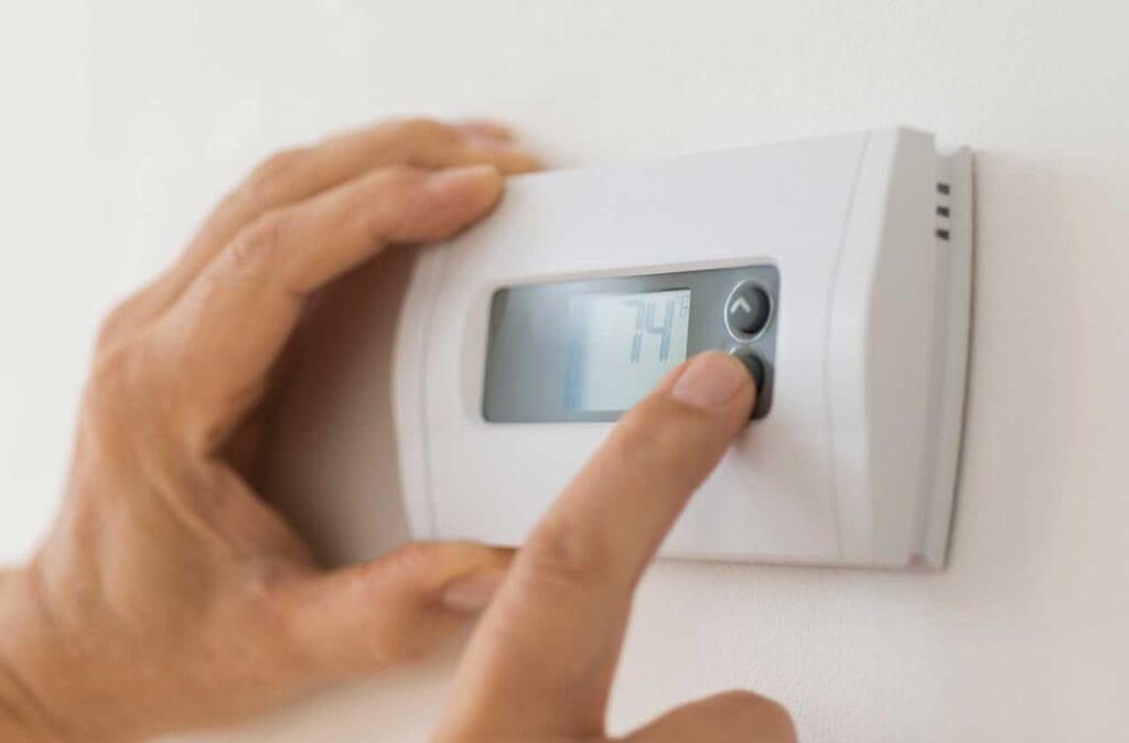 Turning down the heat to save energy using a digital wall thermostat during winter.