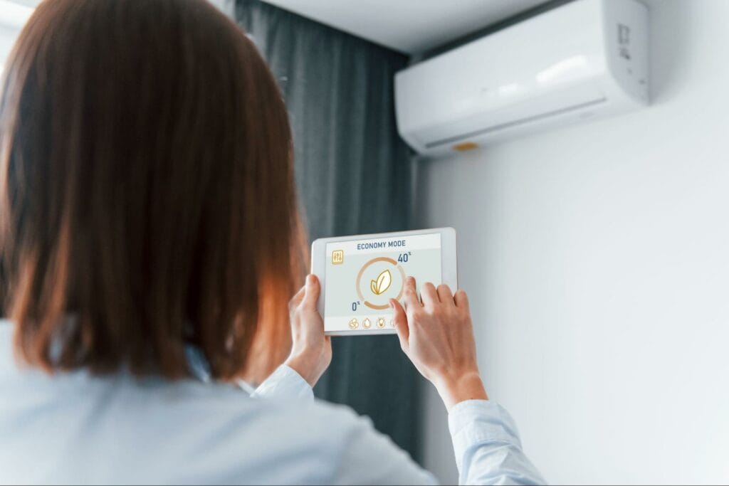 Woman managing air conditioner with a smart control panel in economy mode – helping use the heating mode efficiently.