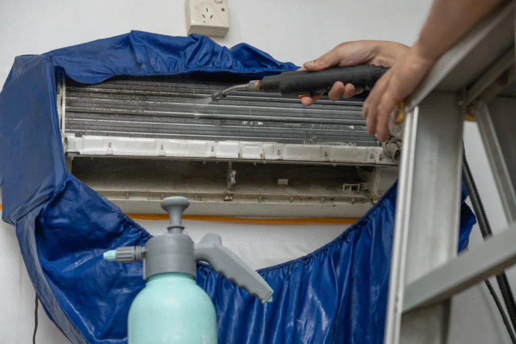 Technician performing Hydro Clean on split air conditioner coils using pressure spray. Professional cleaning service Gold Coast ensuring healthy indoor air.