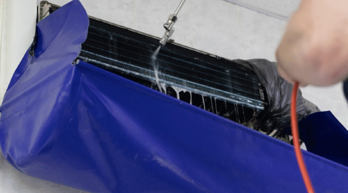 Technician using Hydro Clean chemical clean process with protective cover to deep clean an indoor aircon unit, part of professional air conditioning Gold Coast maintenance.