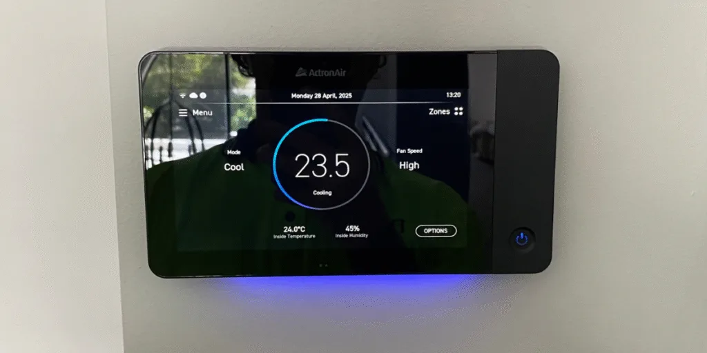 Wall-mounted smart AC controller by ActronAir set to 23.5°C cooling mode, showcasing advanced air conditioning Gold Coast technology compared with old air conditioner units.