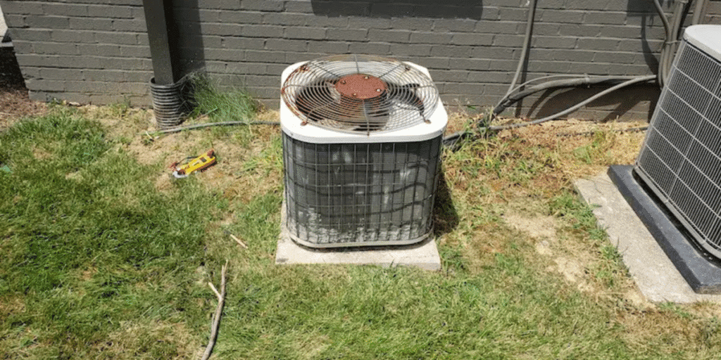 Old, rusty AC condenser outside a house, a clear example of why an air conditioner might not start after winter and how preventative maintenance from air conditioning Gold Coast experts can prevent costly breakdowns.