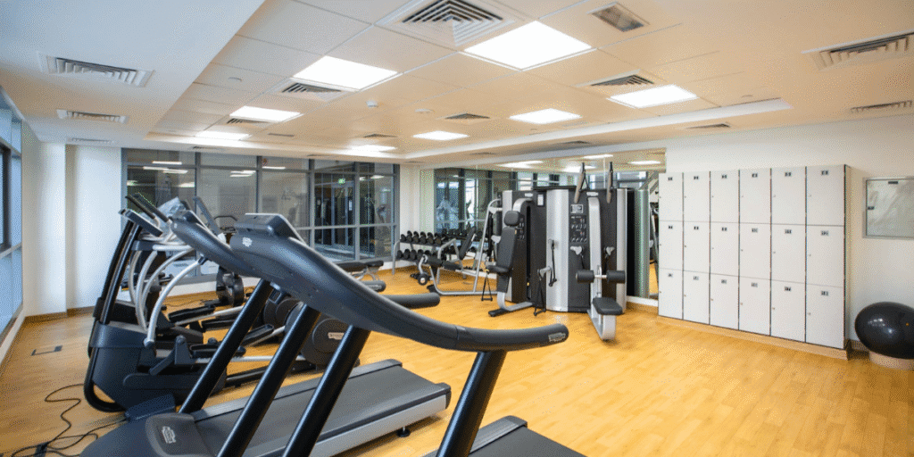 Modern fitness room with treadmills and lockers, featuring ceiling cassette air conditioner placements in gyms for balanced airflow by air conditioning design Gold Coast.