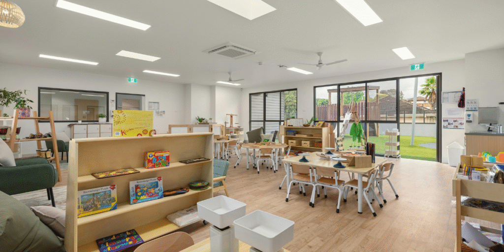 Bright early learning classroom with shelves of books and puzzles, large windows, and reliable air conditioning for childcare centres | air conditioning Gold Coast.