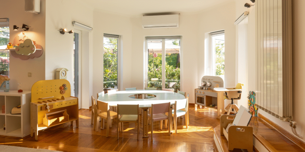 Sunlit childcare playroom with tables and chairs, supported by childcare air conditioners. Regular frequent cleaning and preventative maintenance help ensure safe cooling from air conditioning Gold Coast specialists.