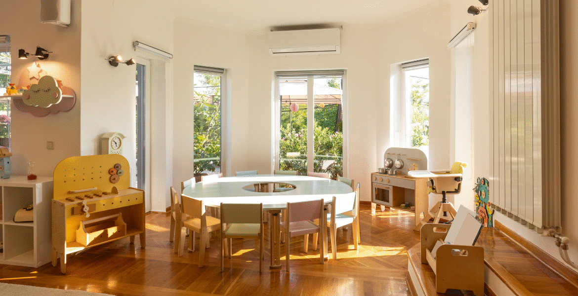 Sunlit childcare playroom with tables and chairs, supported by childcare air conditioners. Regular frequent cleaning and preventative maintenance help ensure safe cooling from air conditioning Gold Coast specialists.