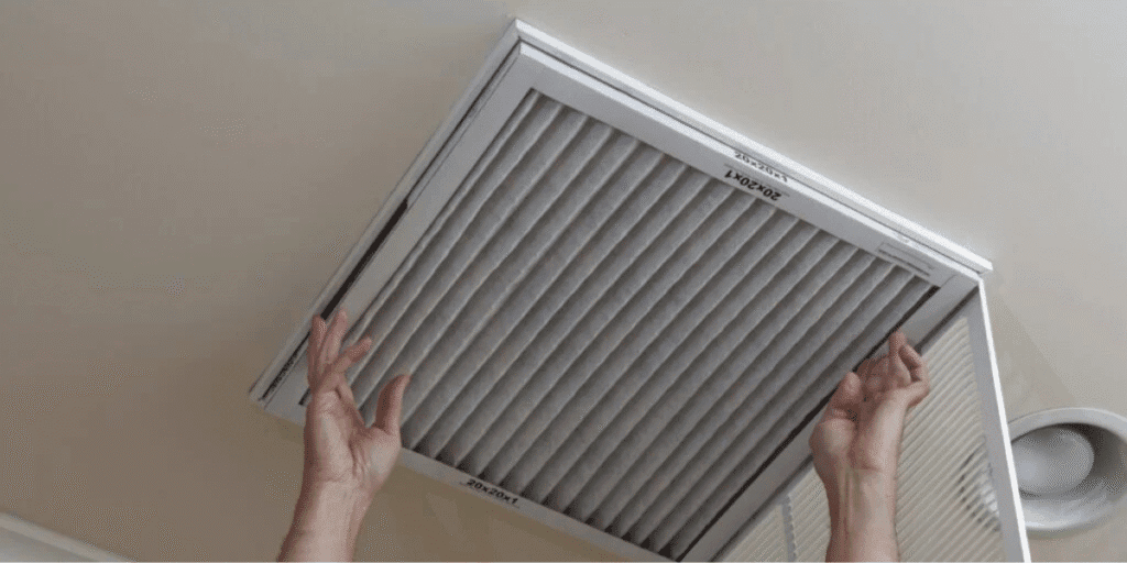 Homeowner showing how to do preventative maintenance by changing air filter, improving efficiency of air conditioning Gold Coast systems.