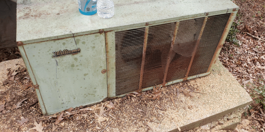 An old outdoor air conditioner unit with rust and debris, showing why it’s risky to use old air conditioner without preventative maintenance in air conditioning Gold Coast.