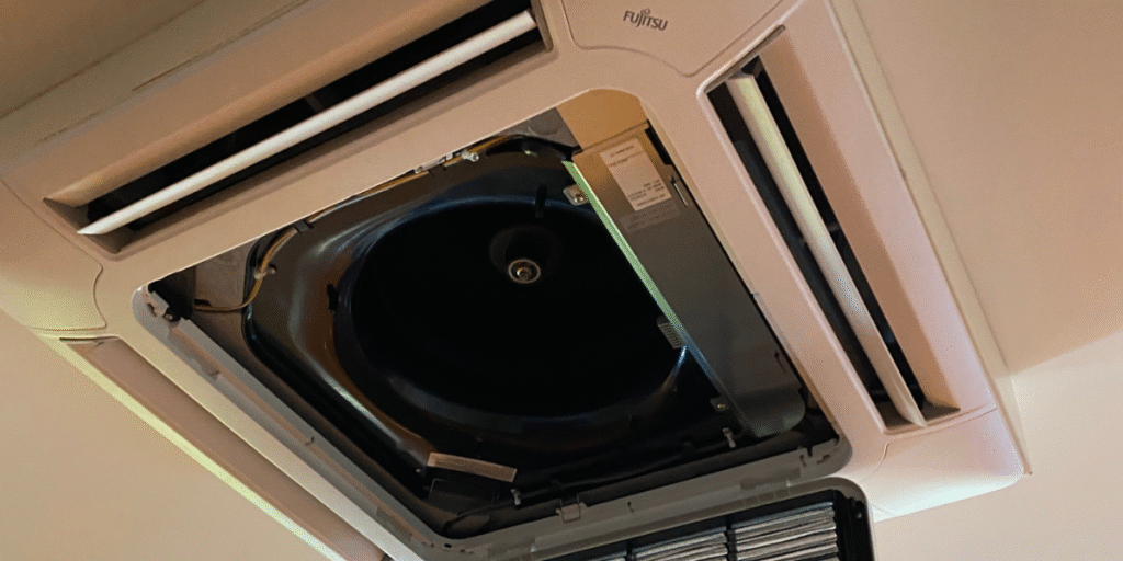 Fujitsu ceiling cassette air conditioner with its indoor fan assembly exposed for maintenance, inspected by a local air conditioning repair service Gold Coast to fix ac indoor fan not spinning faults.