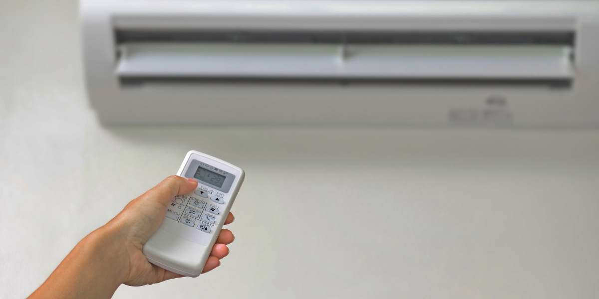 Person using a remote control to operate a wall-mounted air conditioner, checking airflow to confirm if ac indoor fan not spinning issue requires service from an air conditioning repair service Gold Coast.