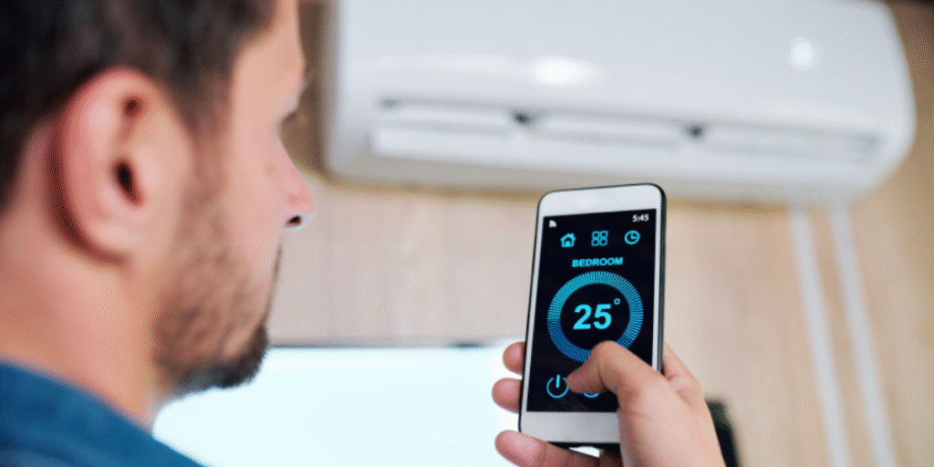 Teacher adjusting classroom temperature with a smartphone app showing 25 °C, demonstrating how smart AC controllers help schools save energy — DEEPCHILL air conditioning Gold Coast experts.