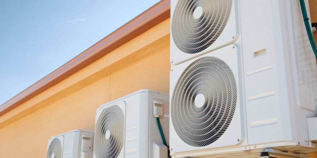 Multiple outdoor air conditioning condensers installed on a building rooftop under blue sky, representing Maintenance Plans for School Air Conditioners by professional air conditioning Gold Coast technicians.