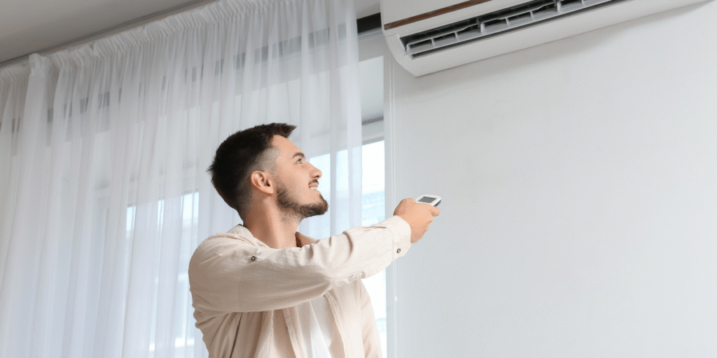 Man adjusting the remote control to set the right temperature for his air conditioner in extreme heat, demonstrating efficient air conditioning Gold Coast usage during high summer temperatures.