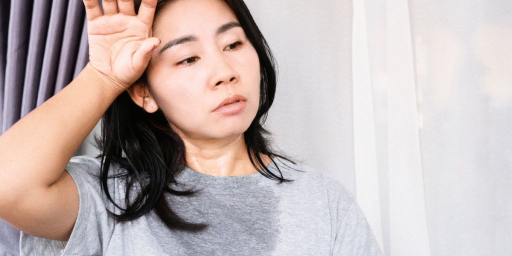A woman sweating indoors because her air conditioner is blowing air but not cooling, showing discomfort in the hot Gold Coast weather and the need for an air conditioning repair service Gold Coast.