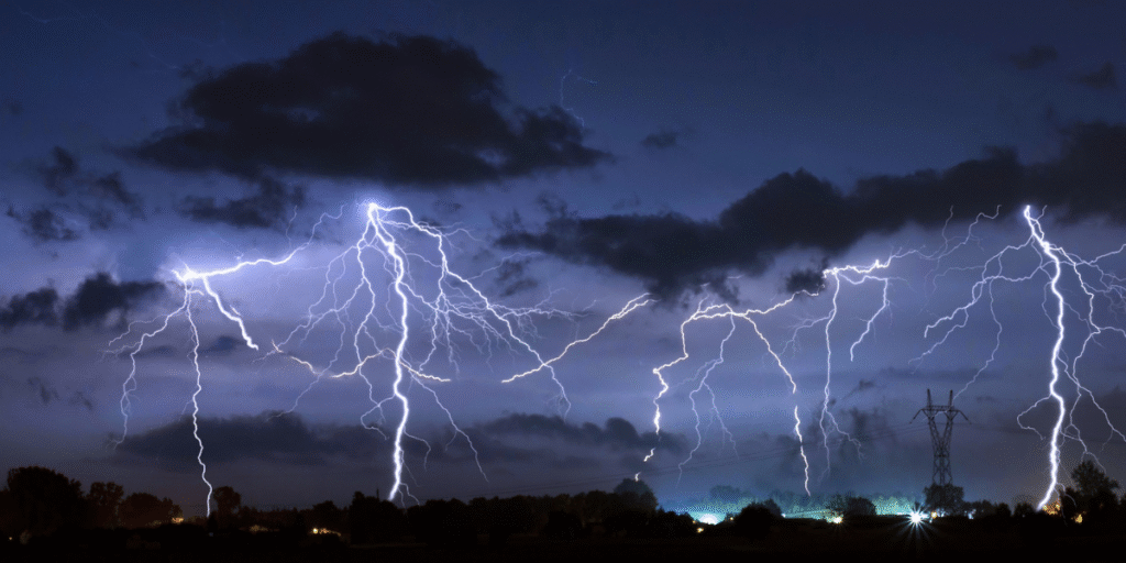 Multiple lightning bolts light up the night sky, showing how severe thunderstorms can cause power surges that damage air conditioners in Gold Coast homes.