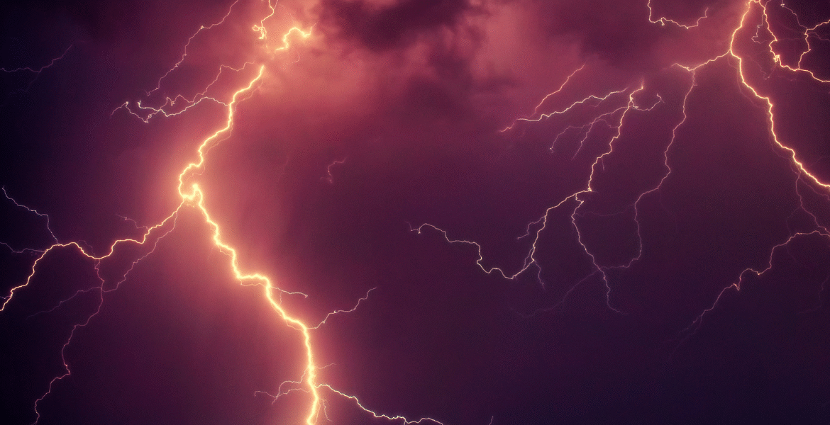 Close-up of powerful lightning strike flashing across the night sky during a thunderstorm — a common cause of power surges that can damage an air conditioner struck by lightning. This weather scene highlights storm risks for air conditioning Gold Coast homes.