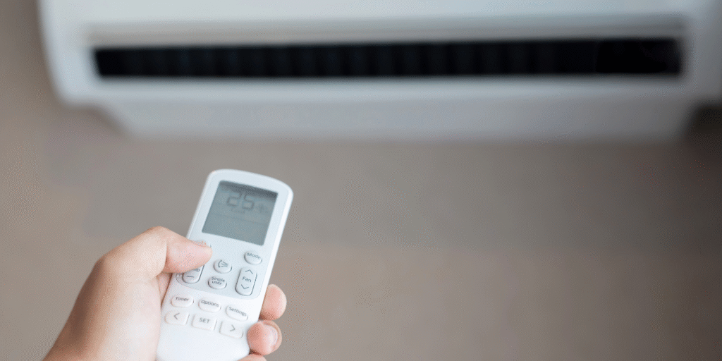 A person uses a remote control to safely shut down the air conditioner during a thunderstorm, preventing damage and ensuring home safety on the Gold Coast.