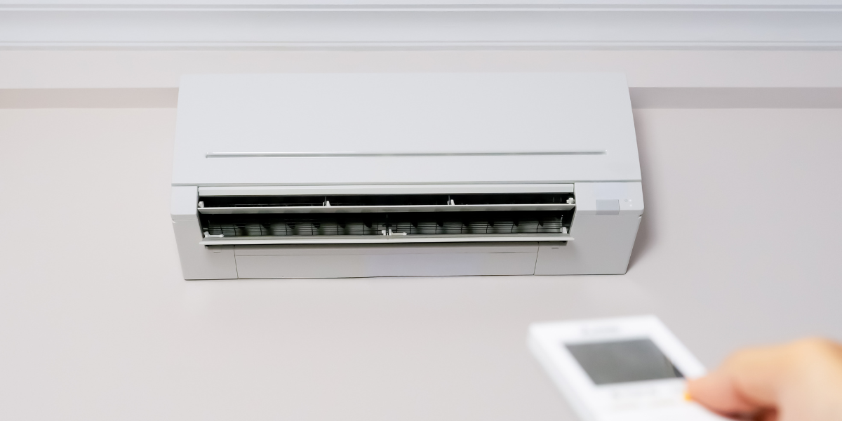 A homeowner turns off the air conditioner with a remote to protect the unit from lightning damage and power surges across the Gold Coast.