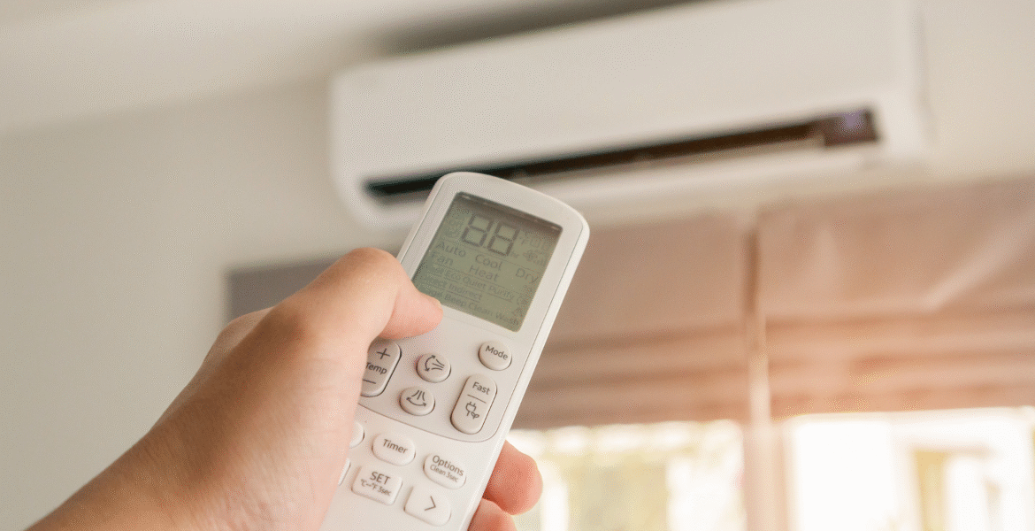 Adjusting the temperature on a remote to cool down an overloaded air conditioner in hot weather inside a Gold Coast home.