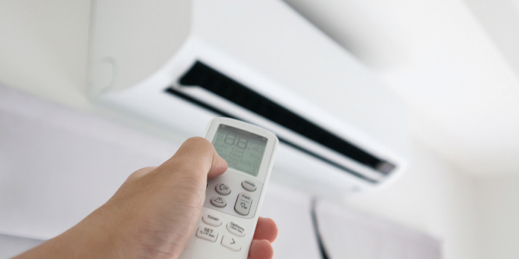 User pointing the remote toward an overloaded air conditioner in hot weather, showing how air conditioning Gold Coast units operate efficiently.