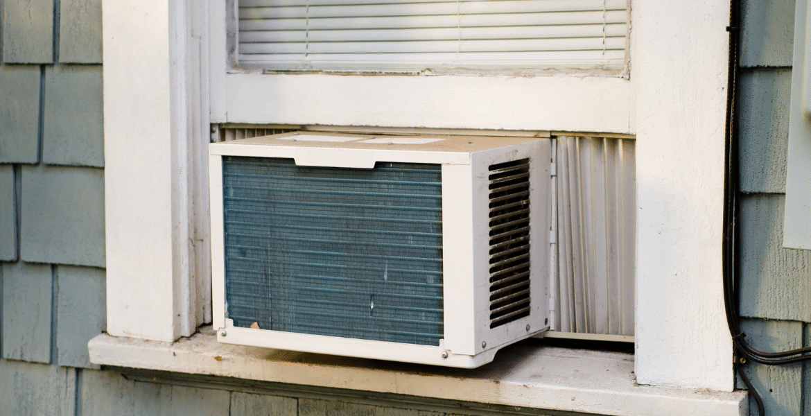An old window air conditioner exposed to heat and rain, showing why homeowners should prevent air conditioner damage in severe weather with proper maintenance by air conditioning Gold Coast experts.