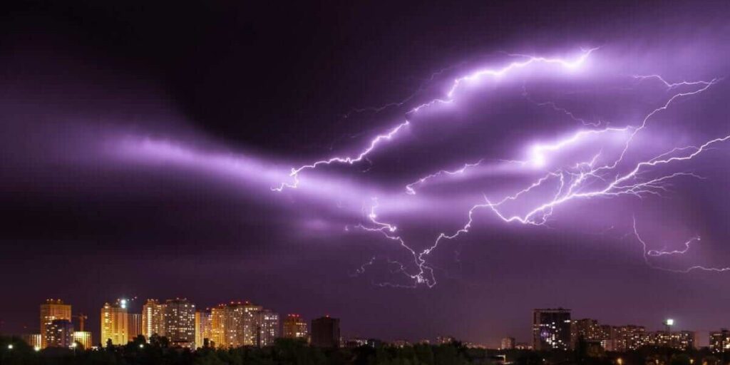 Use air conditioner during thunderstorms in Gold Coast city skyline at night, showing bright lightning above buildings — highlighting air conditioning Gold Coast safety tips.