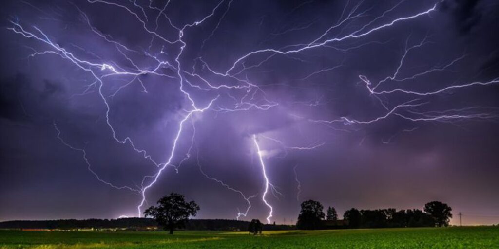 Intense lightning storm over open field — reminder to use air conditioner during thunderstorms safely with expert air conditioning Gold Coast advice.