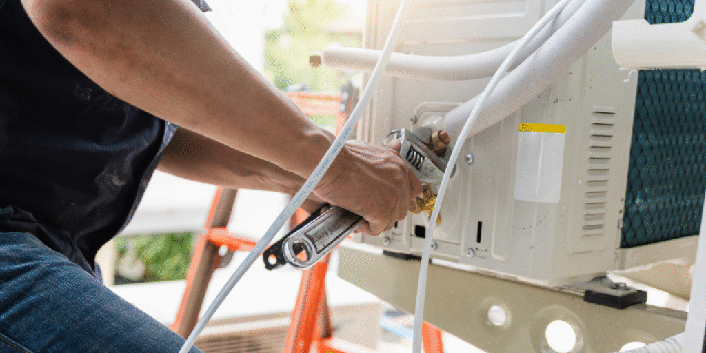 A technician servicing an air conditioner to fix issues caused by AC running nonstop during a heat wave; professional air conditioning Gold Coast maintenance.