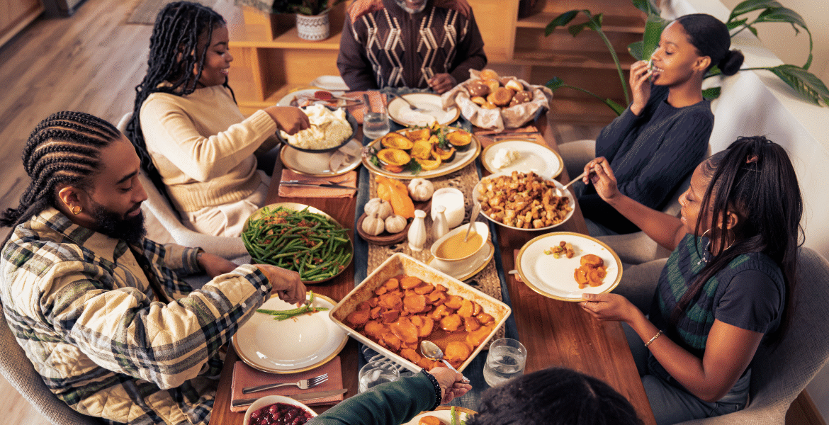 A family gathered around a warm Thanksgiving dinner table, enjoying food together while indoors comfort depends on efficient heating and cooling. This scene highlights how Thanksgiving energy bills rising can impact households and why people look for ways to keep costs low with better home comfort habits, including support from air conditioning Gold Coast services.