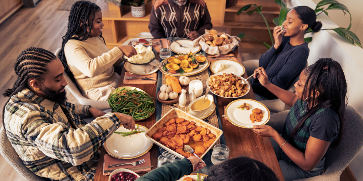 A family gathered around a warm Thanksgiving dinner table, enjoying food together while indoors comfort depends on efficient heating and cooling. This scene highlights how Thanksgiving energy bills rising can impact households and why people look for ways to keep costs low with better home comfort habits, including support from air conditioning Gold Coast services.