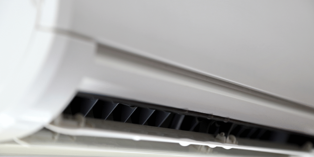 Close-up of an indoor split-system AC unit with visible water droplets forming along the drip tray, showing an air conditioner leaking water during the holiday. DEEPCHILL – air conditioning Gold Coast and commercial air conditioning Gold Coast specialists.