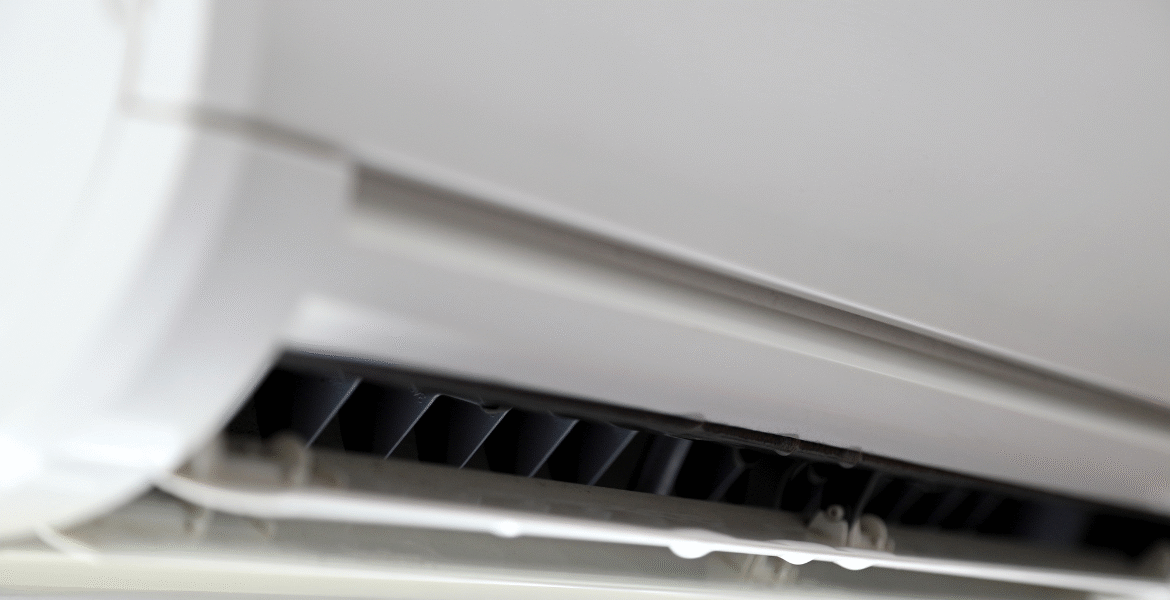 Close-up of an indoor split-system AC unit with visible water droplets forming along the drip tray, showing an air conditioner leaking water during the holiday. DEEPCHILL – air conditioning Gold Coast and commercial air conditioning Gold Coast specialists.
