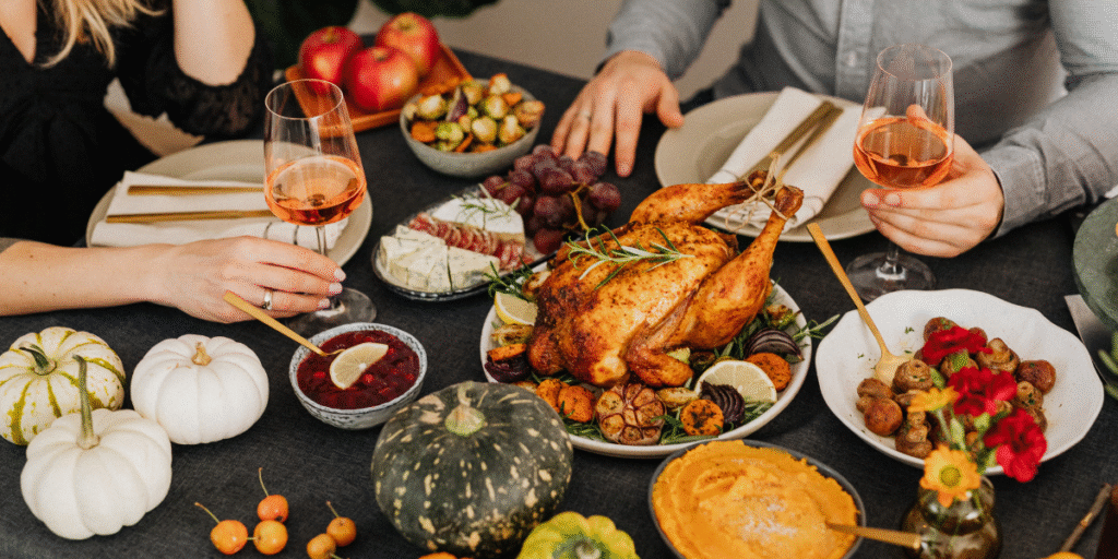 A Thanksgiving meal setup with roast turkey, vegetables, wine, and festive pumpkins, showing how rich holiday cooking scents can linger indoors and lead to air conditioner smells after cooking for Thanksgiving, highlighting the importance of well-maintained air conditioning Gold Coast units and regular air conditioning servicing Gold Coast.
