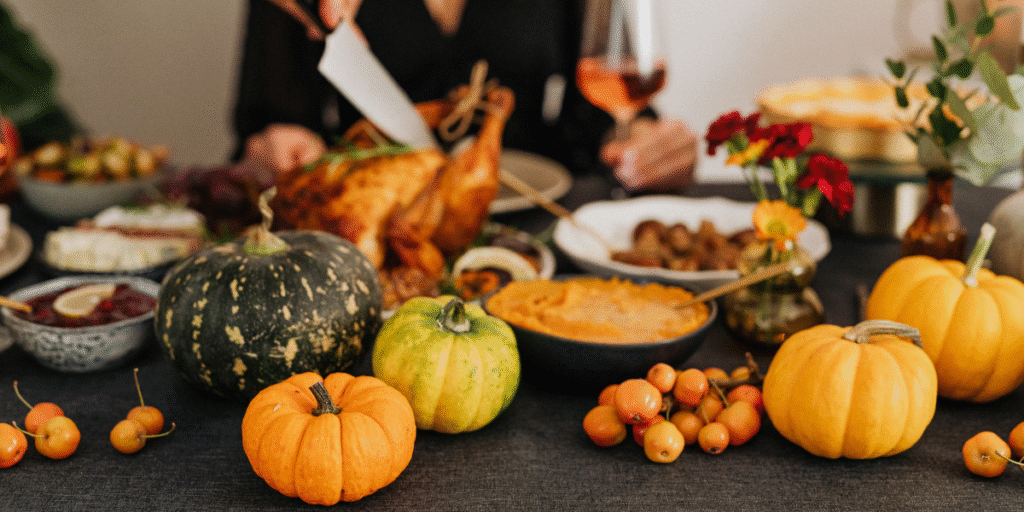 A cozy Thanksgiving dinner table filled with pumpkins, roast turkey, and autumn dishes, illustrating how strong kitchen aromas can cause air conditioner smells after cooking for Thanksgiving without proper ventilation, especially in homes using air conditioning Gold Coast systems that may need timely air conditioning servicing Gold Coast.