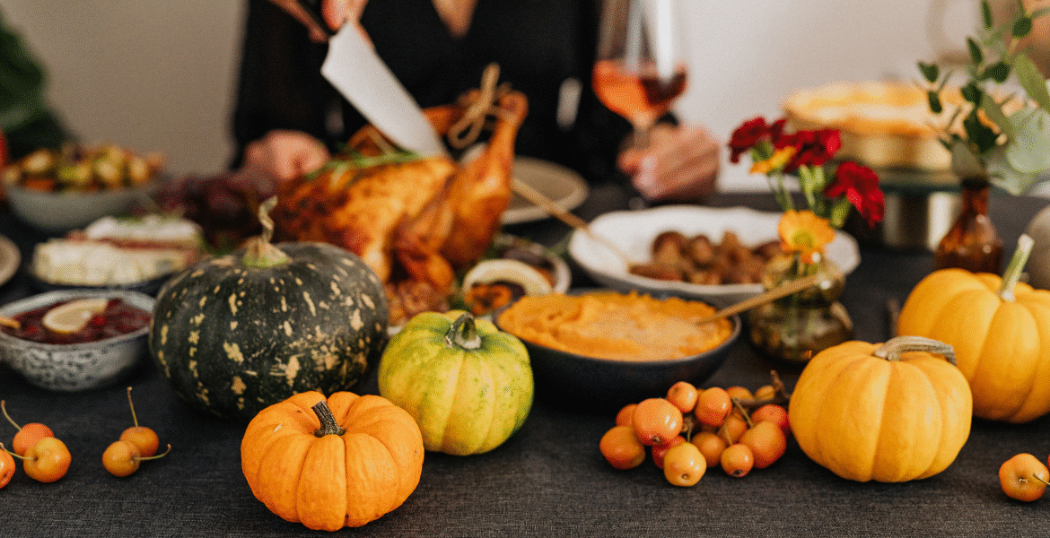 A cozy Thanksgiving dinner table filled with pumpkins, roast turkey, and autumn dishes, illustrating how strong kitchen aromas can cause air conditioner smells after cooking for Thanksgiving without proper ventilation, especially in homes using air conditioning Gold Coast systems that may need timely air conditioning servicing Gold Coast.