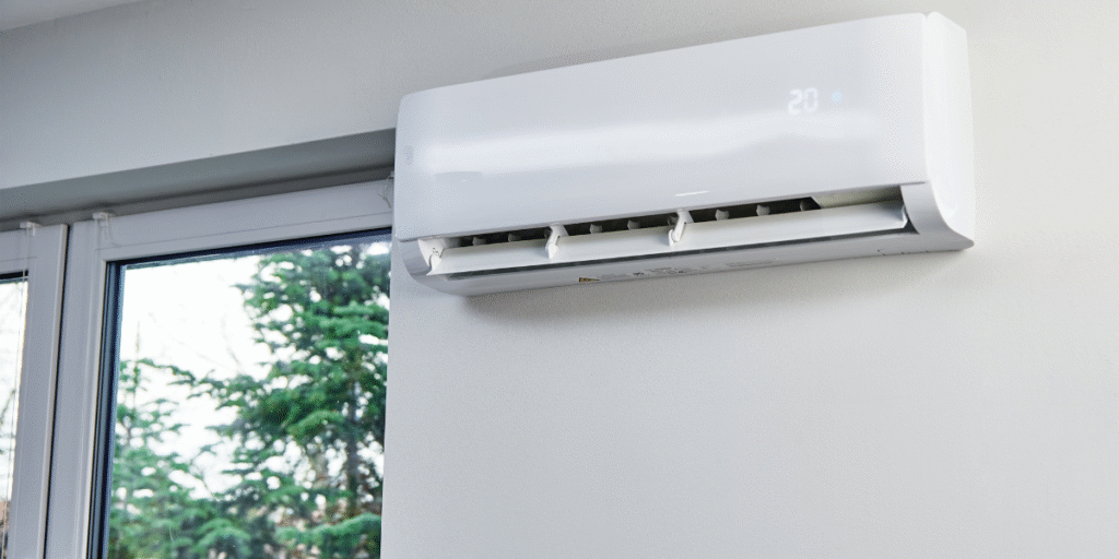 A wall-mounted split system blowing cool air inside a bright room, illustrating why many people leave your air conditioner all day during hot weather, especially in air conditioning Gold Coast homes.